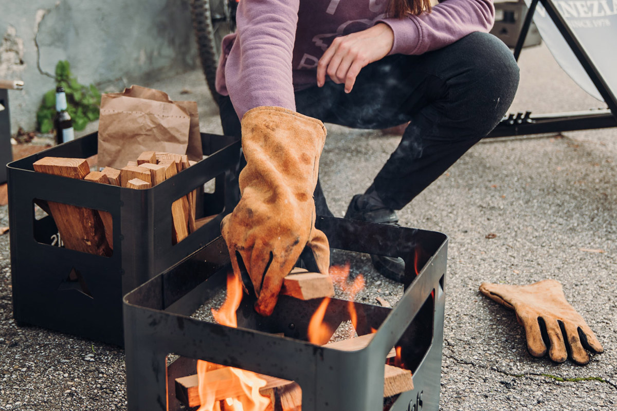 Lägger ned ved i Beer Box Eldkorg med Höfats Grillhandskar på
