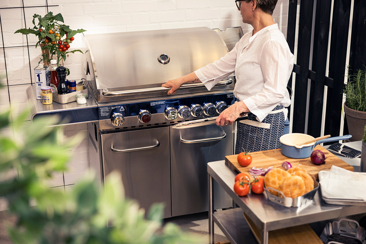 Kvinna lyfter lock på Bluegaz Z5 Gasolgrill